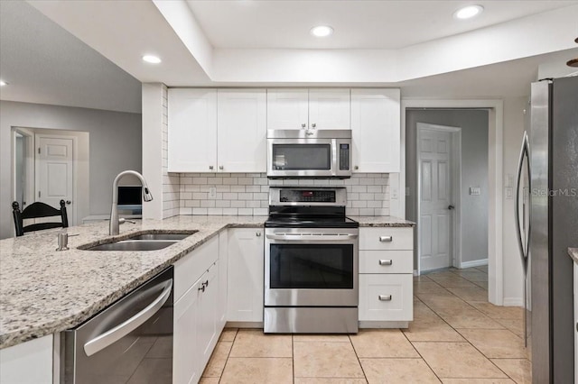 kitchen featuring white cabinets, appliances with stainless steel finishes, a sink, and tasteful backsplash