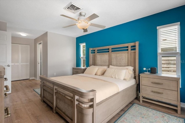 bedroom with a textured ceiling, a closet, visible vents, and light wood-style floors