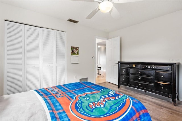bedroom featuring a closet, a ceiling fan, visible vents, and wood finished floors