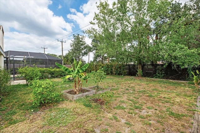 view of yard featuring a vegetable garden, fence, and a lanai