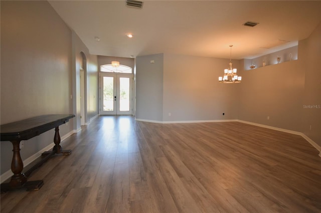 entryway with visible vents, wood finished floors, baseboards, a chandelier, and arched walkways