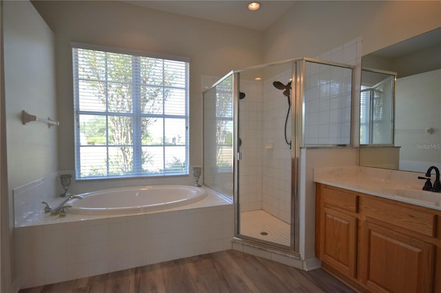 bathroom featuring wood finished floors, a bath, a stall shower, and vanity