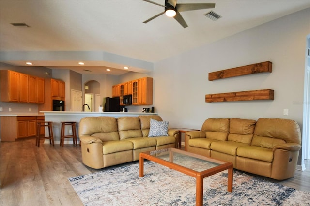 living area featuring a ceiling fan, visible vents, arched walkways, light wood-style floors, and recessed lighting