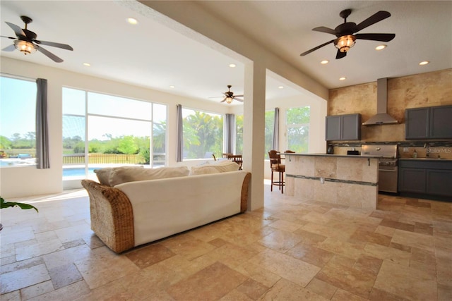 living room with a ceiling fan, recessed lighting, and stone tile flooring