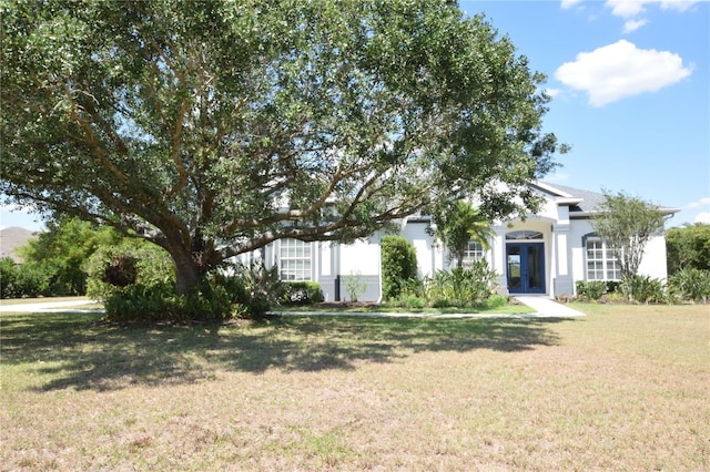 obstructed view of property featuring stucco siding, french doors, and a front yard