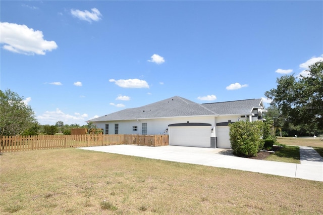 exterior space featuring a garage, a front lawn, fence, and driveway