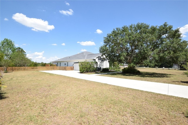 view of yard featuring fence, driveway, and a garage