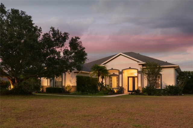 ranch-style house featuring a yard and stucco siding