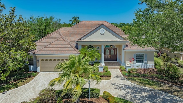 view of front of home featuring an attached garage, decorative driveway, stucco siding, and covered porch