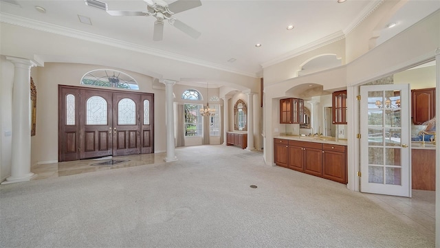 entrance foyer with crown molding, light colored carpet, and decorative columns