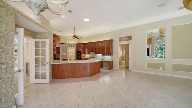 kitchen featuring a ceiling fan, light countertops, light tile patterned floors, a peninsula, and ornamental molding