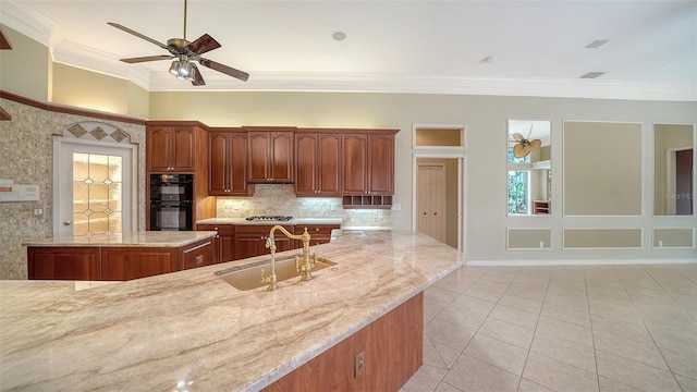 kitchen featuring crown molding, light stone counters, a sink, dobule oven black, and a ceiling fan