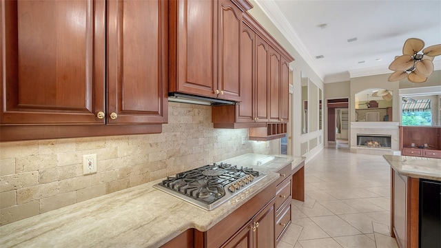 kitchen with crown molding, ceiling fan, stainless steel gas cooktop, decorative backsplash, and light tile patterned floors