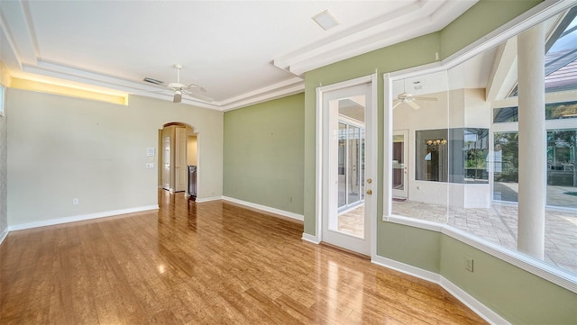 spare room with ceiling fan, visible vents, arched walkways, wood finished floors, and baseboards
