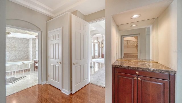 bathroom with a tub to relax in, recessed lighting, wood finished floors, and vanity