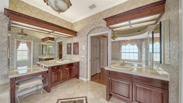 full bathroom with visible vents, crown molding, two vanities, a sink, and wallpapered walls