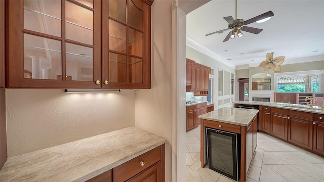 kitchen featuring a ceiling fan, crown molding, a sink, light tile patterned floors, and glass insert cabinets