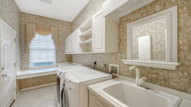 washroom with cabinet space, a sink, wallpapered walls, light tile patterned floors, and washing machine and dryer