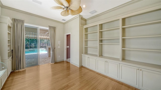 spare room featuring light wood-type flooring, ornamental molding, a ceiling fan, and visible vents