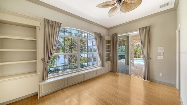 empty room featuring light wood-type flooring, a ceiling fan, visible vents, and ornamental molding