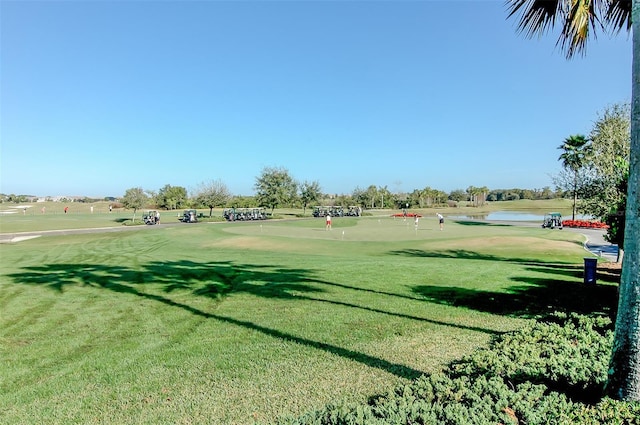 view of property's community featuring a yard, a water view, and view of golf course