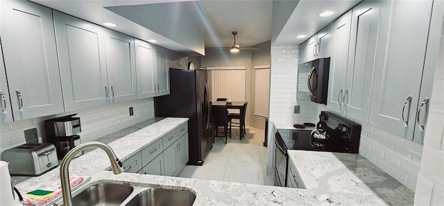 4415 45th Ave W Unit 203, Bradenton, FL 34210 - kitchen featuring light stone counters, a sink, a ceiling fan, tasteful backsplash, and black appliances