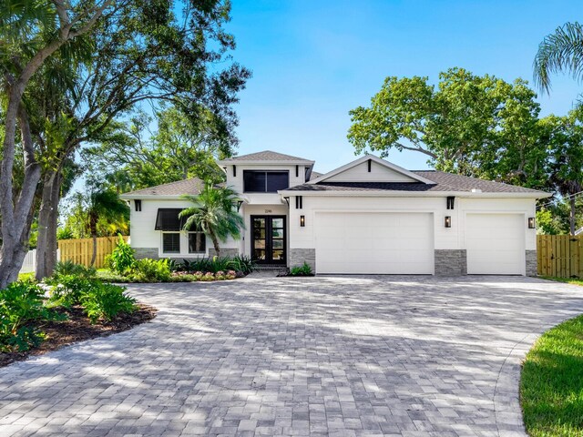 2246 Webber St, Sarasota, FL 34239 - view of front facade featuring french doors, stone siding, a garage, fence, and decorative driveway