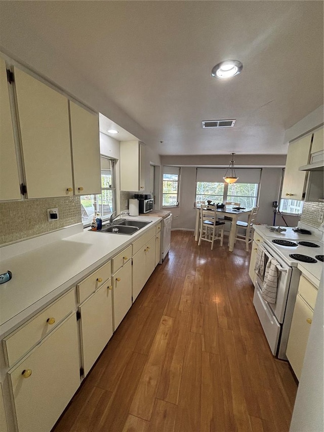 4411 Dolphin Ln, Palmetto, FL 34221 - kitchen with white range with electric stovetop, light countertops, hardwood / wood-style floors, tasteful backsplash, and visible vents