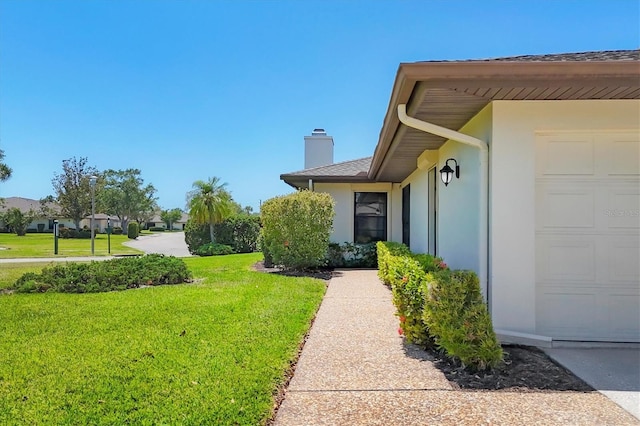 7374 Royal Birkdale Dr Unit 15D, Sarasota, FL 34238 - exterior space featuring a lawn, stucco siding, a chimney, and a garage
