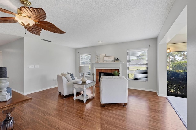 7374 Royal Birkdale Dr Unit 15D, Sarasota, FL 34238 - living room with a textured ceiling, a wealth of natural light, wood finished floors, and a fireplace