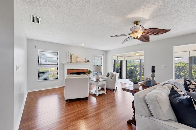 7374 Royal Birkdale Dr Unit 15D, Sarasota, FL 34238 - living room featuring a tiled fireplace, plenty of natural light, a textured ceiling, and visible vents