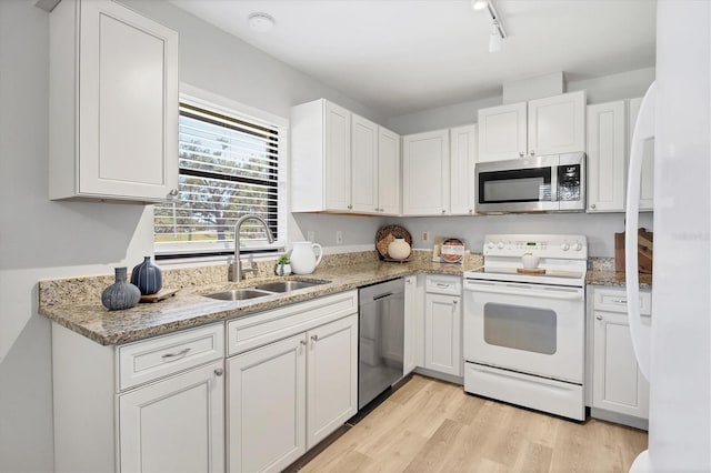 7374 Royal Birkdale Dr Unit 15D, Sarasota, FL 34238 - kitchen with light stone countertops, appliances with stainless steel finishes, a sink, light wood finished floors, and white cabinetry