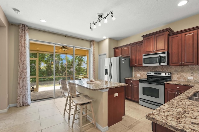 27243 Ipswich Dr, Englewood, FL 34223 - kitchen featuring light tile patterned floors, appliances with stainless steel finishes, decorative backsplash, and light stone counters
