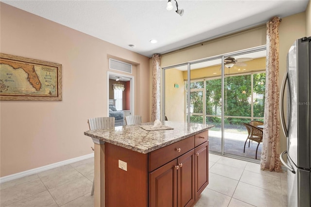 27243 Ipswich Dr, Englewood, FL 34223 - kitchen with light tile patterned floors, light stone counters, baseboards, and freestanding refrigerator