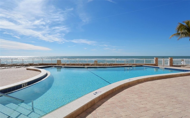 community pool featuring a water view and fence