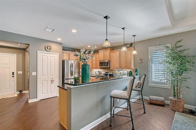 12133 Forest Park Cir, Bradenton, FL 34211 - kitchen featuring stainless steel appliances, dark wood-style floors, dark countertops, a breakfast bar area, and baseboards