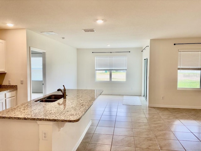 kitchen with a sink, a wealth of natural light, white cabinets, and visible vents
