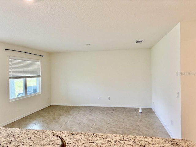 empty room featuring light tile patterned floors, baseboards, and visible vents