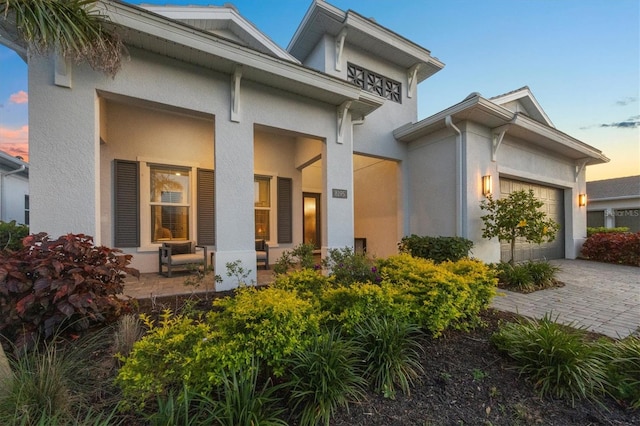 8195 Redonda Loop, Lakewood Ranch, FL 34202 - exterior space featuring a porch, decorative driveway, an attached garage, and stucco siding