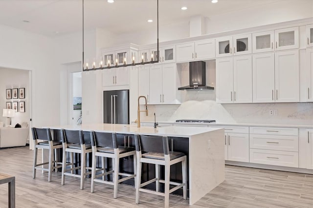8195 Redonda Loop, Lakewood Ranch, FL 34202 - kitchen with wall chimney range hood, a sink, high end fridge, white cabinetry, and an island with sink