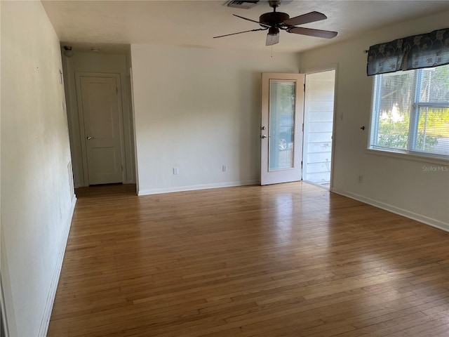 spare room with baseboards, a ceiling fan, visible vents, and hardwood / wood-style flooring