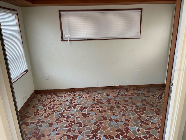 spare room featuring baseboards, plenty of natural light, and wooden walls