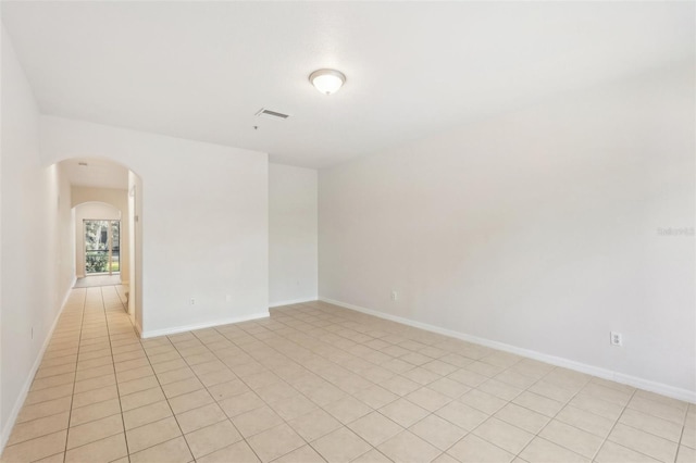 unfurnished room featuring baseboards, arched walkways, and visible vents