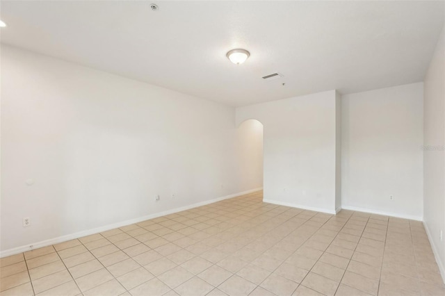 empty room with visible vents, arched walkways, and baseboards