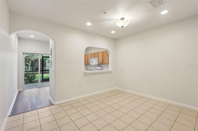 unfurnished room with recessed lighting, baseboards, visible vents, and arched walkways