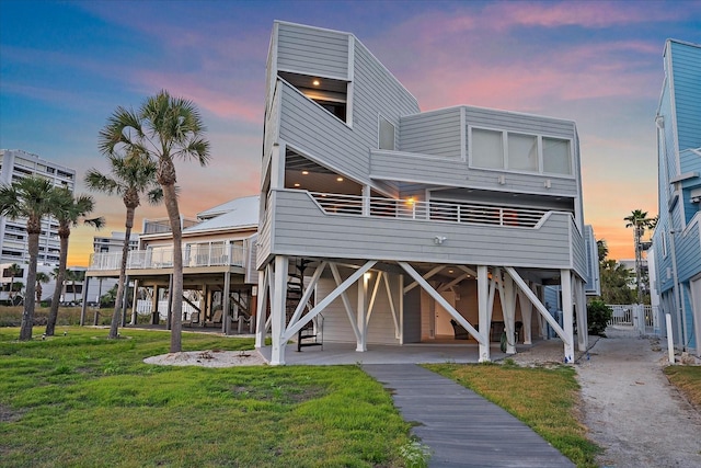 rear view of house featuring a lawn and stairs