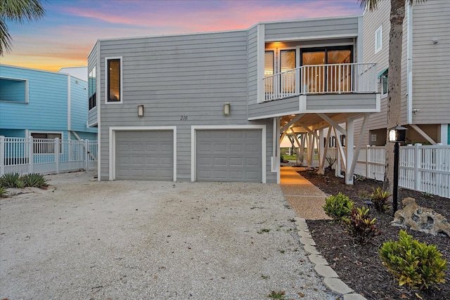back of house featuring a garage, gravel driveway, and fence