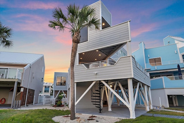 back of house at dusk with a carport, stairs, and a balcony