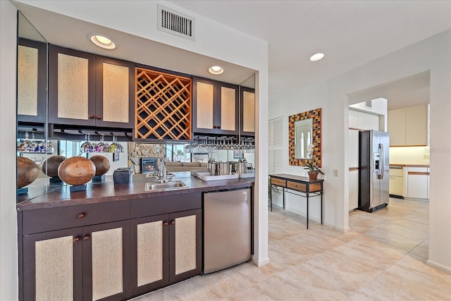 bar area with fridge, stainless steel fridge, recessed lighting, light tile patterned floors, and a sink