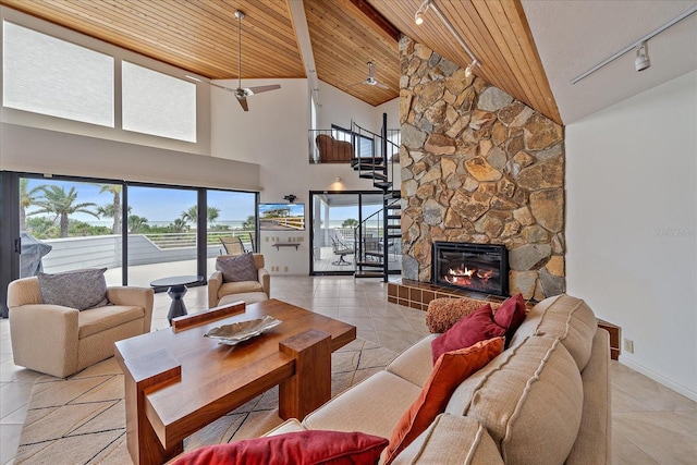 living room with track lighting, wooden ceiling, high vaulted ceiling, a stone fireplace, and light tile patterned floors